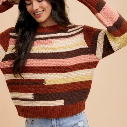 Multicolored striped patchwork sweater with jeans and tan hat