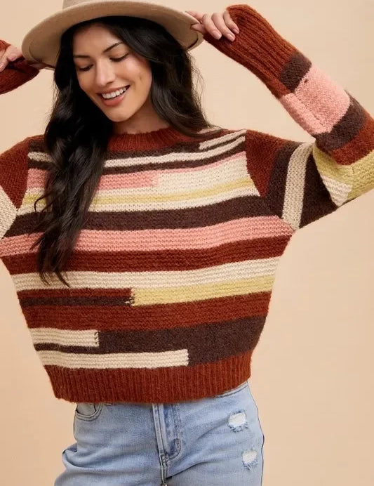 Multicolored striped patchwork sweater with jeans and tan hat