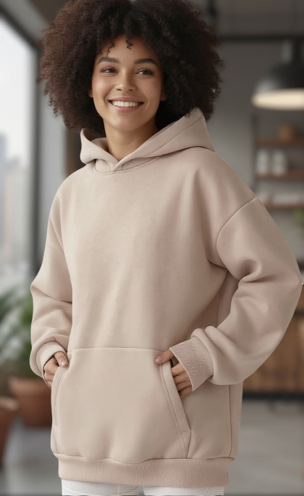 A woman wearing a beige kangaroo pocket hoodie 