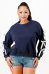 A woman wearing a navy blue crewneck sweatshirt with white bows on sleeves