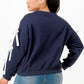 Back view of a woman wearing a navy blue crewneck sweatshirt with white bows on sleeves