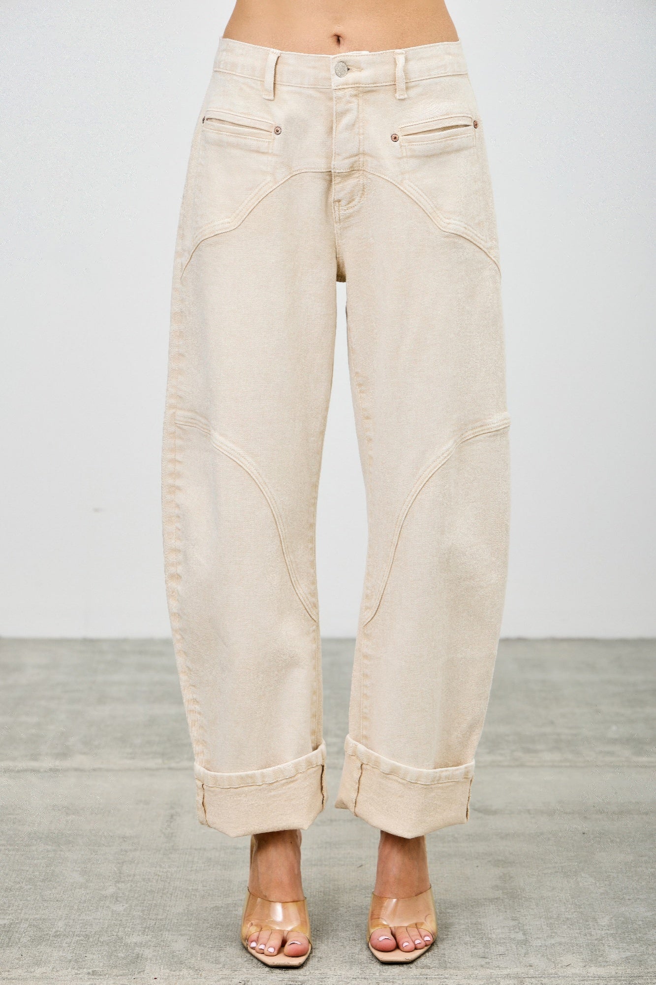 High-rise beige wide-leg denim pants with rolled cuffs and stitched paneling