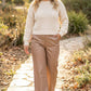 Woman in cream knit sweater and faux leather wide-leg tan pants