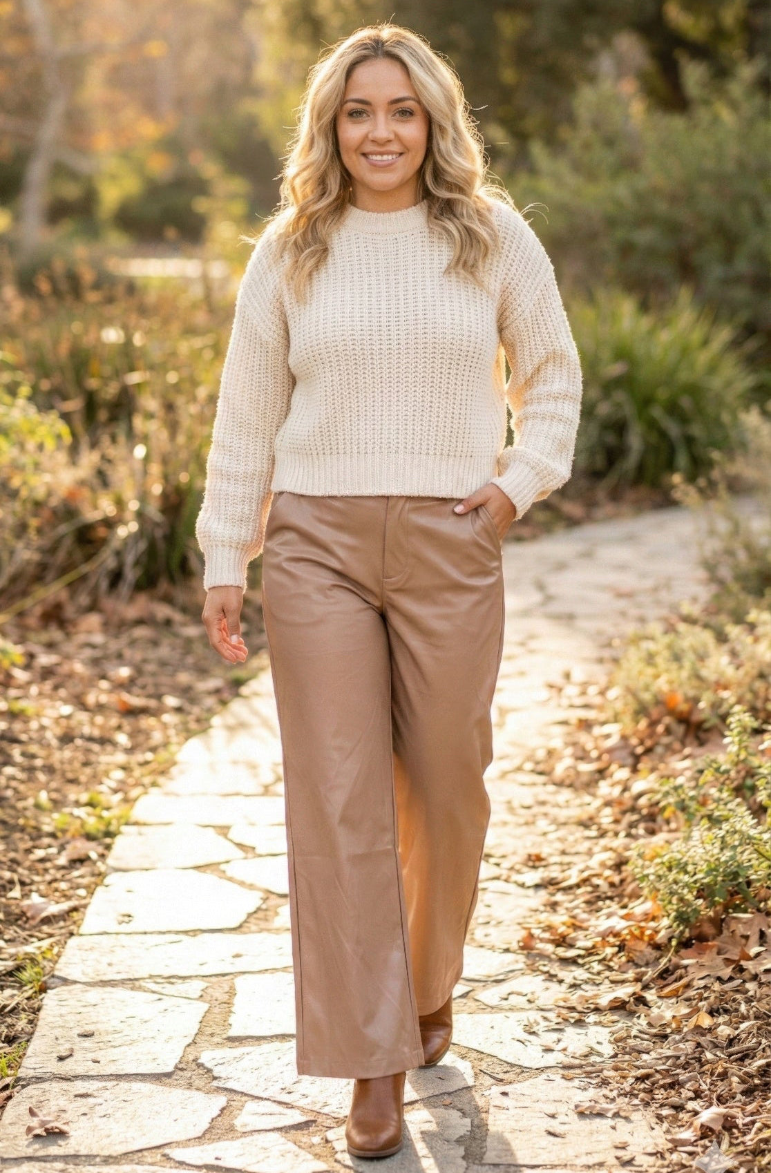 Woman in cream knit sweater and faux leather wide-leg tan pants