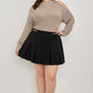 Plus size cold-shoulder knit sweater with black pleated mini skirt and gold belt buckle