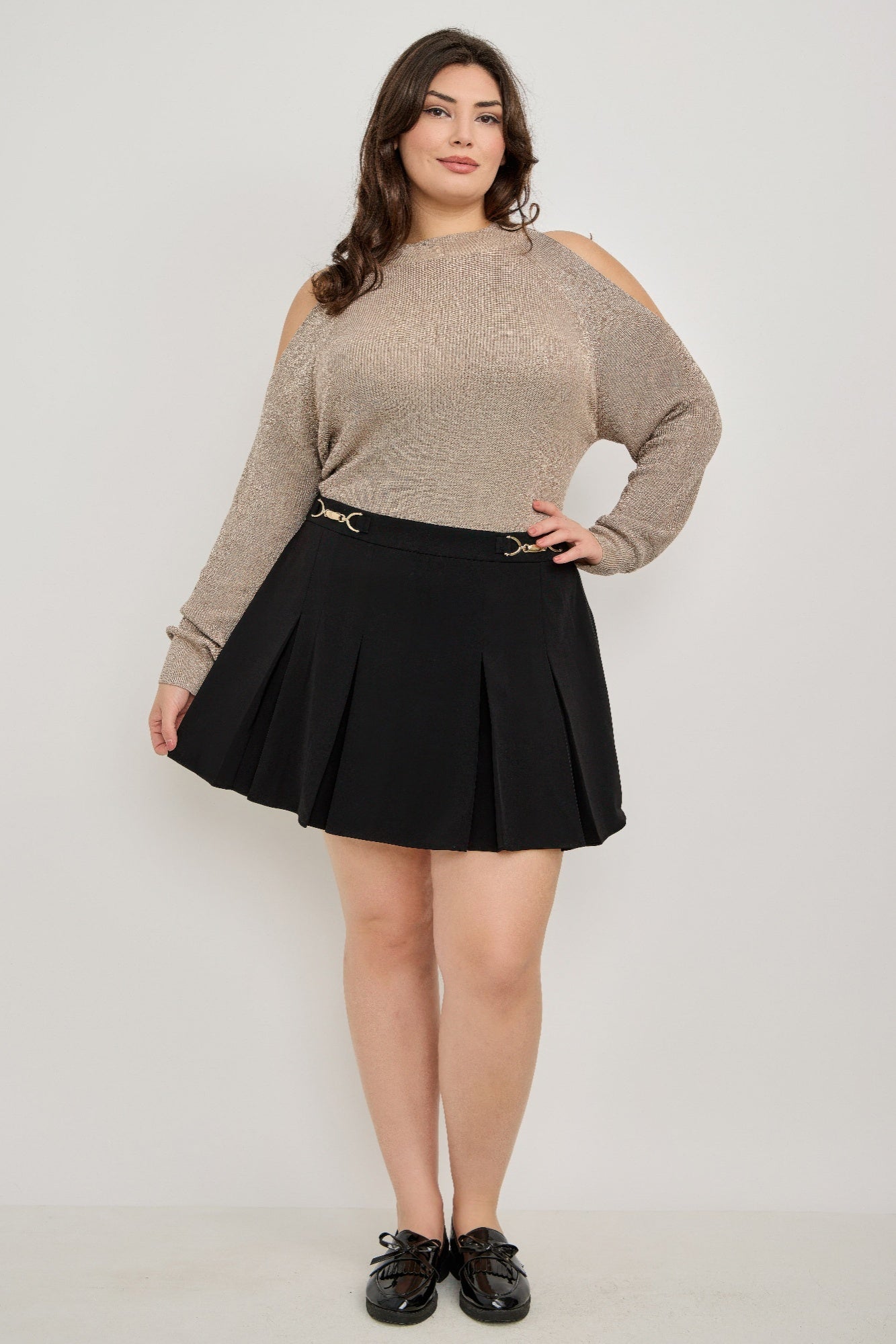 Plus size cold-shoulder knit sweater with black pleated mini skirt and gold belt buckle