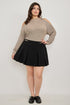 Plus size cold-shoulder knit sweater with black pleated mini skirt and gold belt buckle