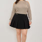Black pleated mini skirt with gold-tone belt buckle on plus size cold-shoulder knit sweater