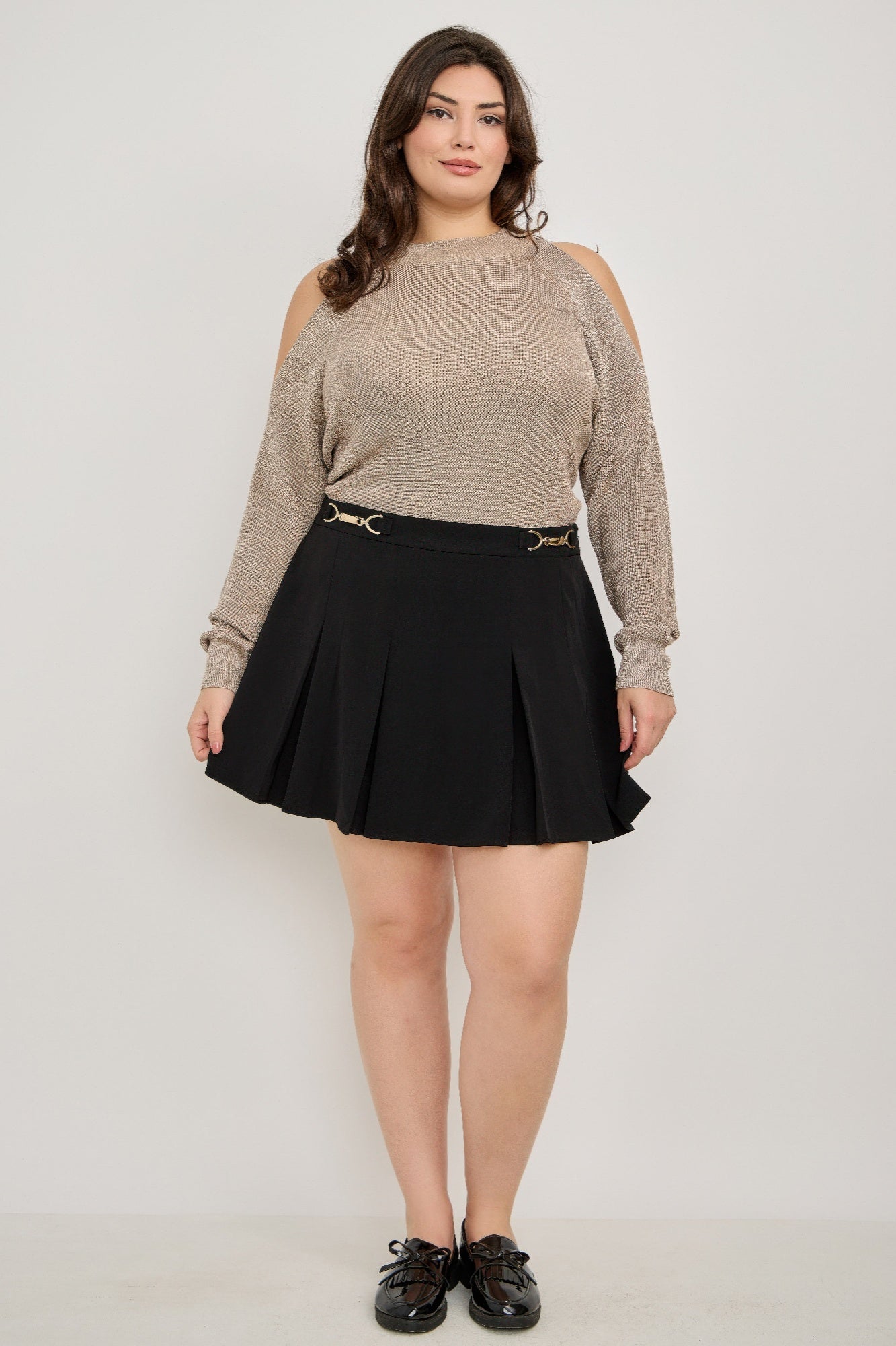 Black pleated mini skirt with gold-tone belt buckle on plus size cold-shoulder knit sweater