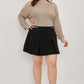 Black pleated mini skirt with gold-tone belt buckle for plus size cold-shoulder knit sweater
