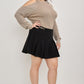 Black pleated mini skirt with sleek tailored fit and cold-shoulder knit sweater