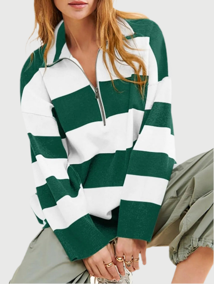 Person wearing a green and white striped sweater on a plain background