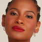 A woman wearing gold-colored and cz mariner link earrings  against a neutral background