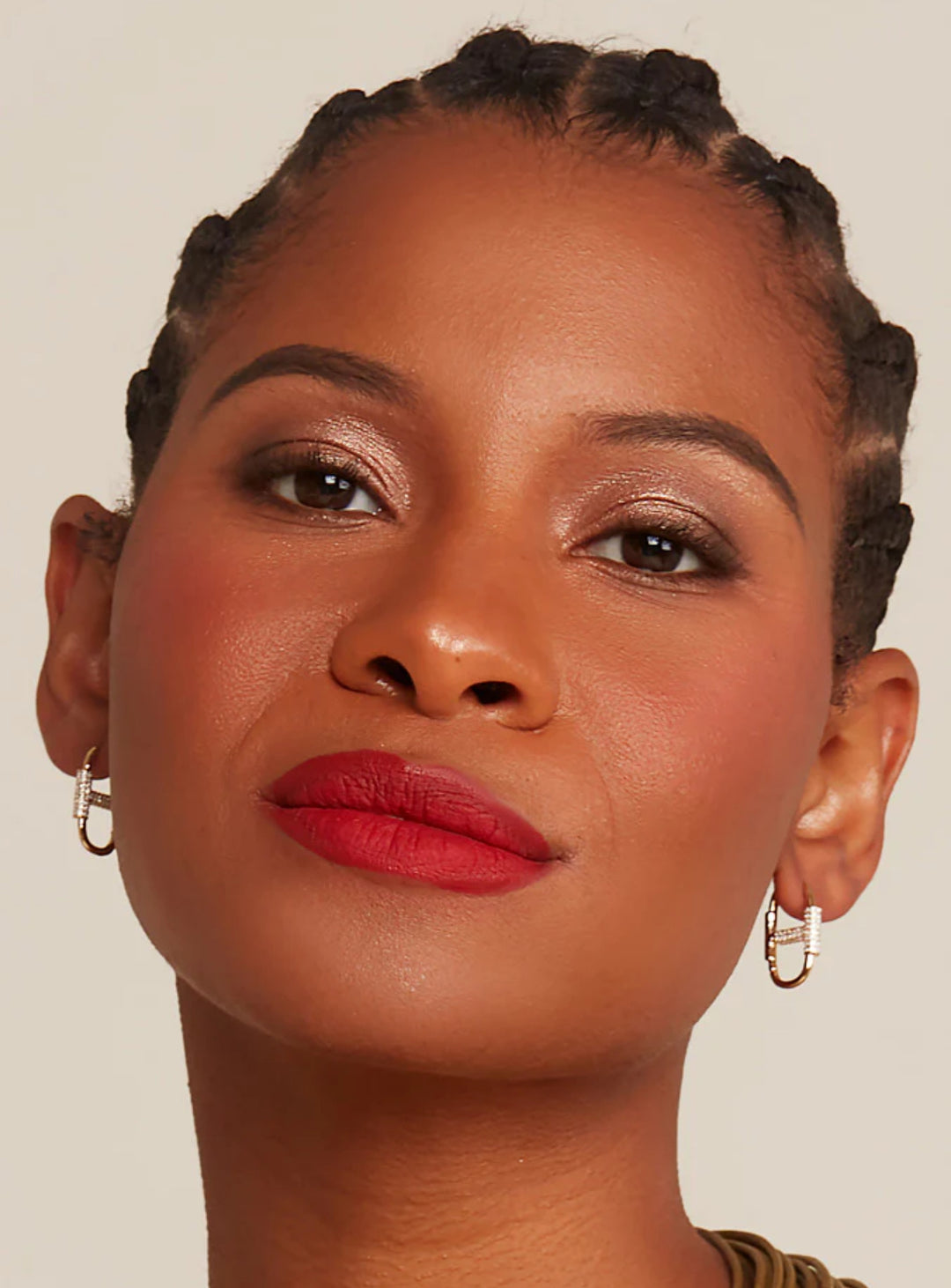 A woman wearing gold-colored and cz mariner link earrings  against a neutral background