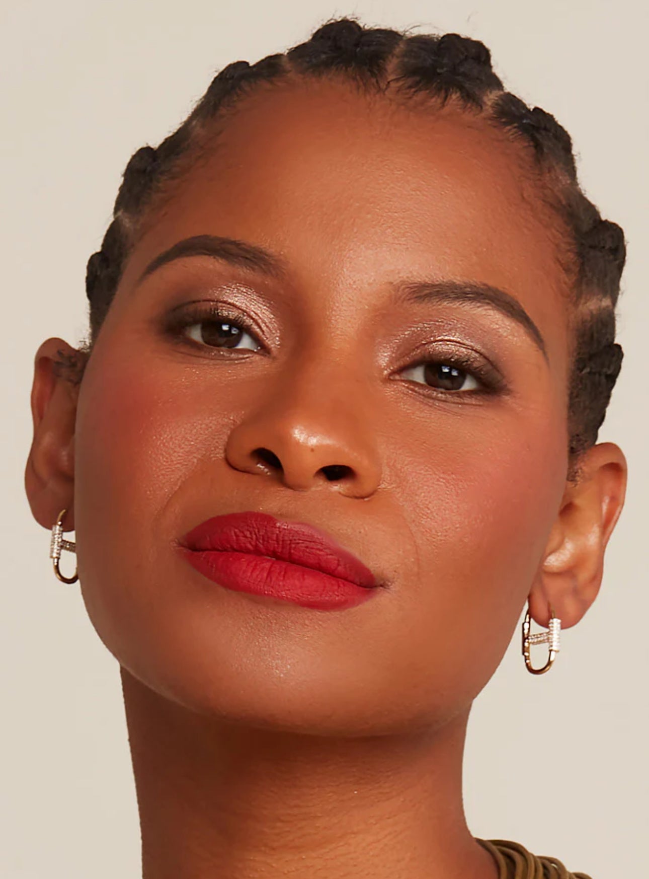 A woman wearing gold-colored and cz mariner link earrings  against a neutral background