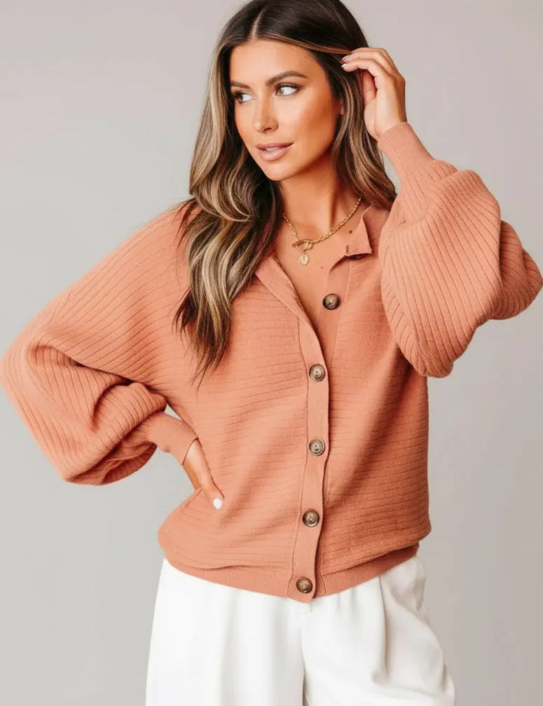 Woman wearing a coral colored cardigan sweater
