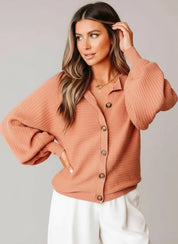 Woman wearing a coral colored cardigan sweater