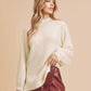 Cream-colored, fluffy knit sweater with a high neckline and long sleeves.