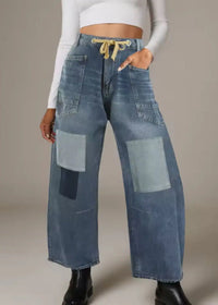 Person wearing wide-leg patchwork jeans on a neutral background