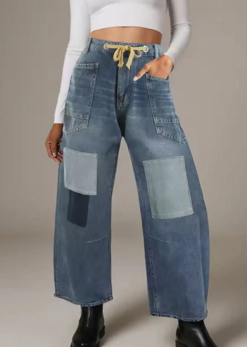 Person wearing wide-leg patchwork jeans on a neutral background
