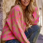 A cozy, oversized camel-colored knit sweater with vibrant pink and orange leopard print pattern.