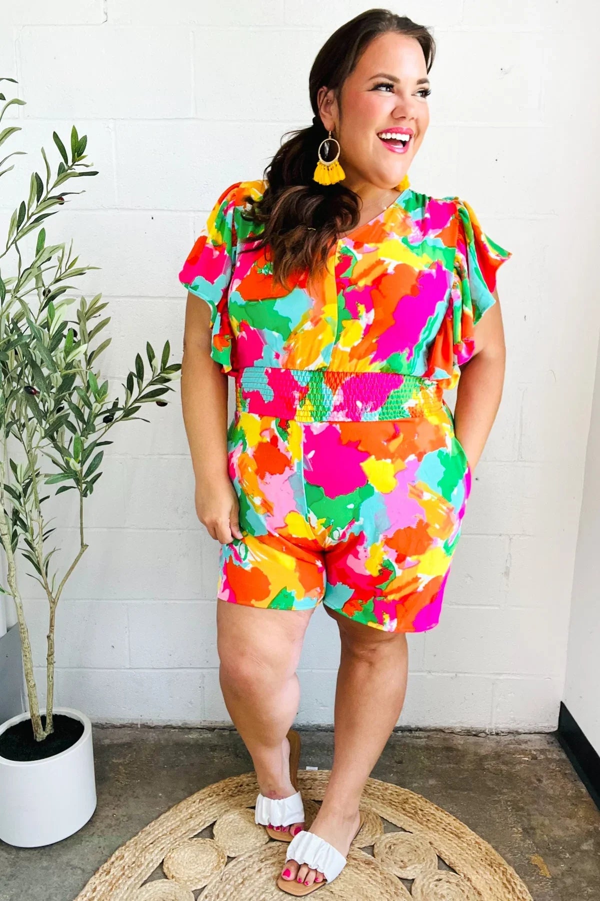 Multicolored abstract floral smocked waist V-neck romper with ruffled sleeves and white sandals