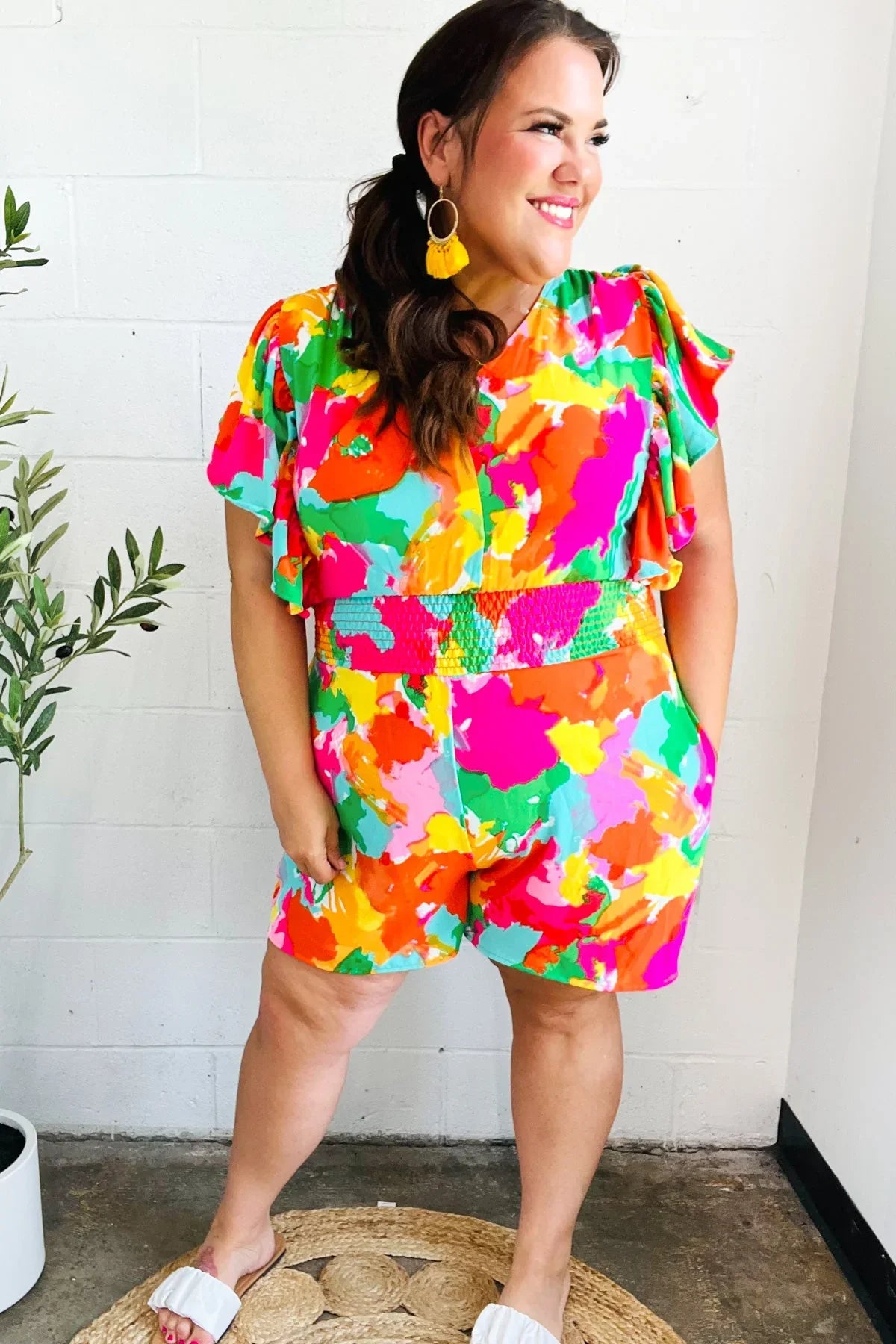 Multicolored abstract floral romper with ruffled sleeves and yellow earrings