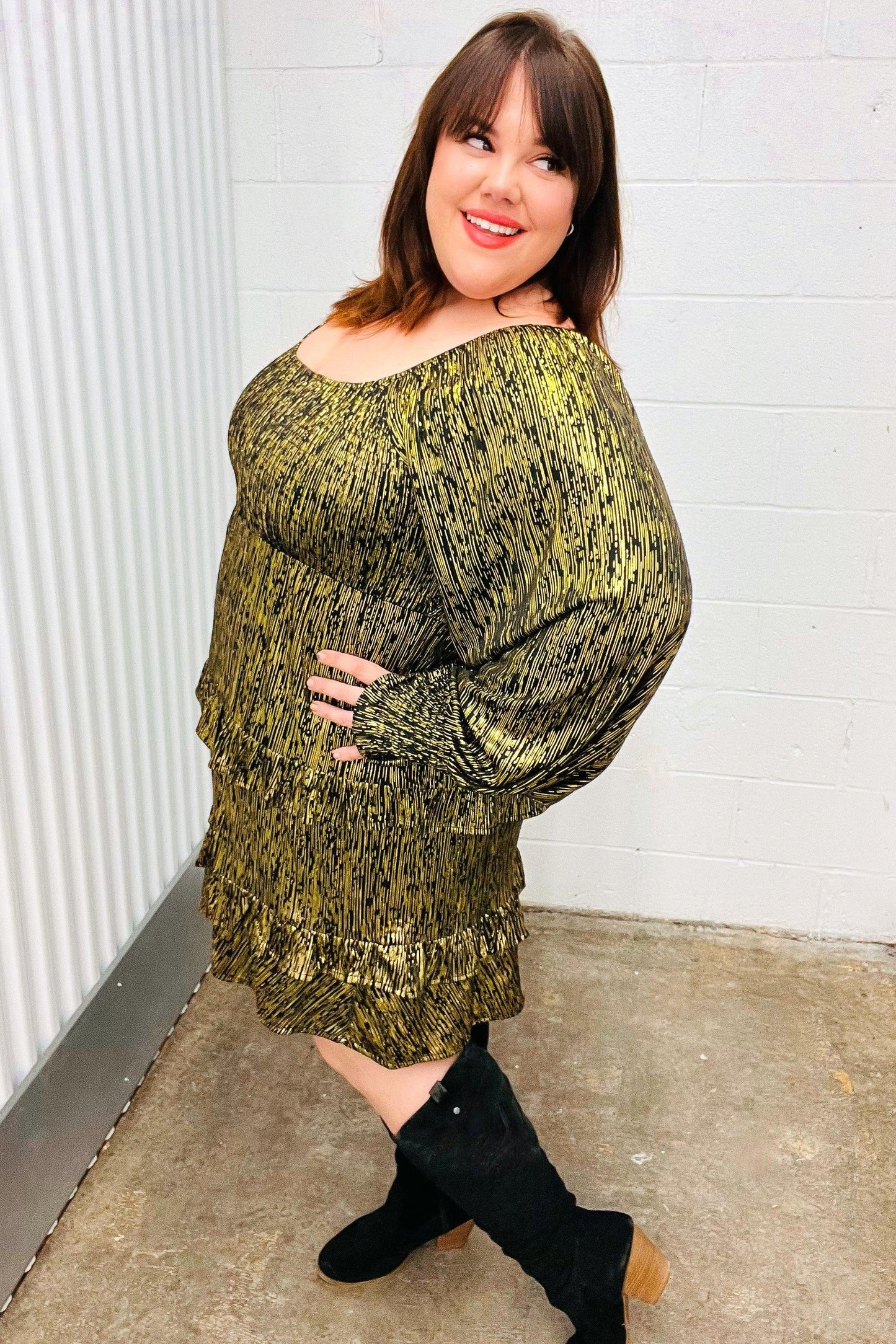 Olive green textured sweater dress with black boots on white wall