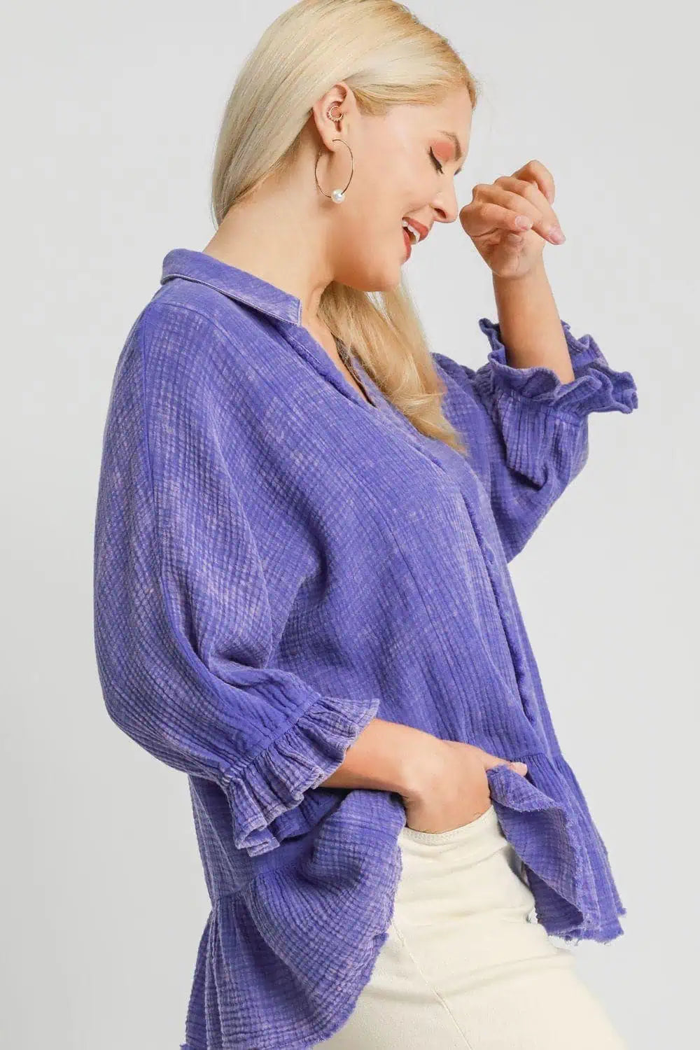 A woman wearing a purple gauze top smiling