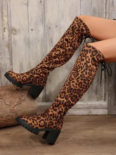 A woman wearing knee high leopard print boots