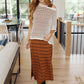 Woman in cream Coastal Dreams fishnet top with striped skirt