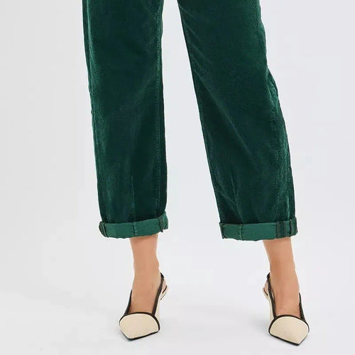 Green pants with rolled-up cuffs worn by a person on a white background