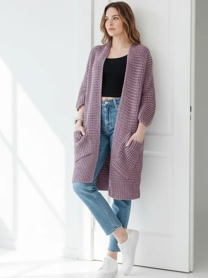 Woman wearing a soft lavender chunky knit open-front cardigan with a waffle texture and large side pockets, paired with jeans.