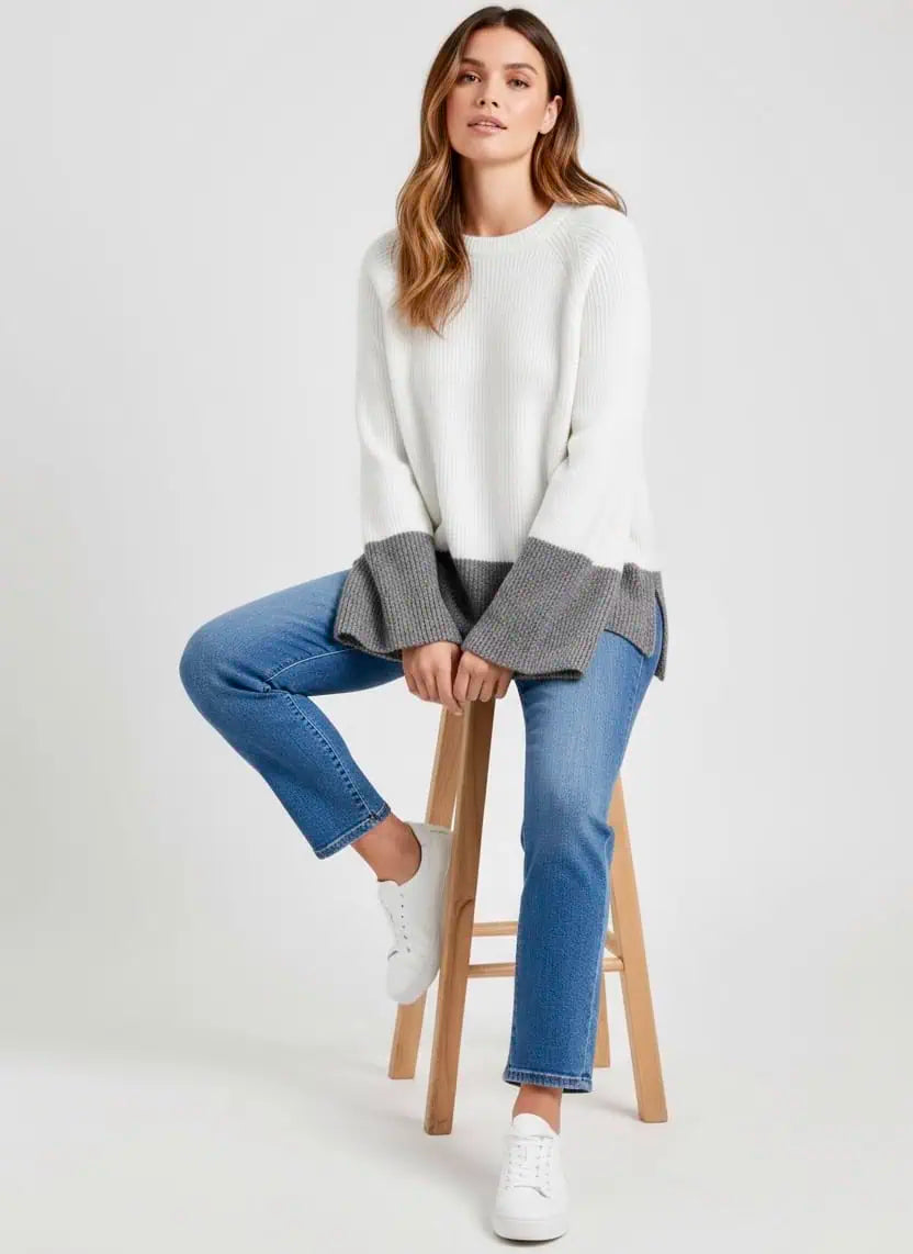 Woman sitting on a stool in a fall sweater and jeans