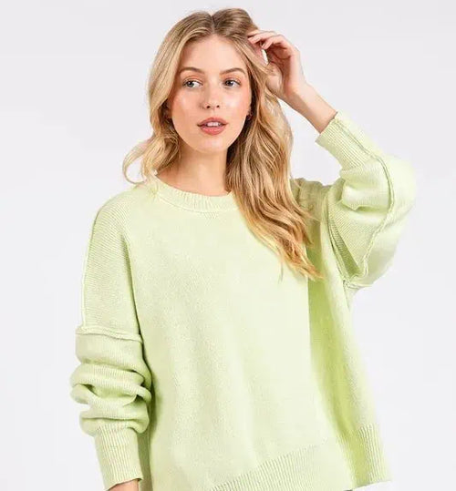 Woman wearing a light green sweater against a plain background