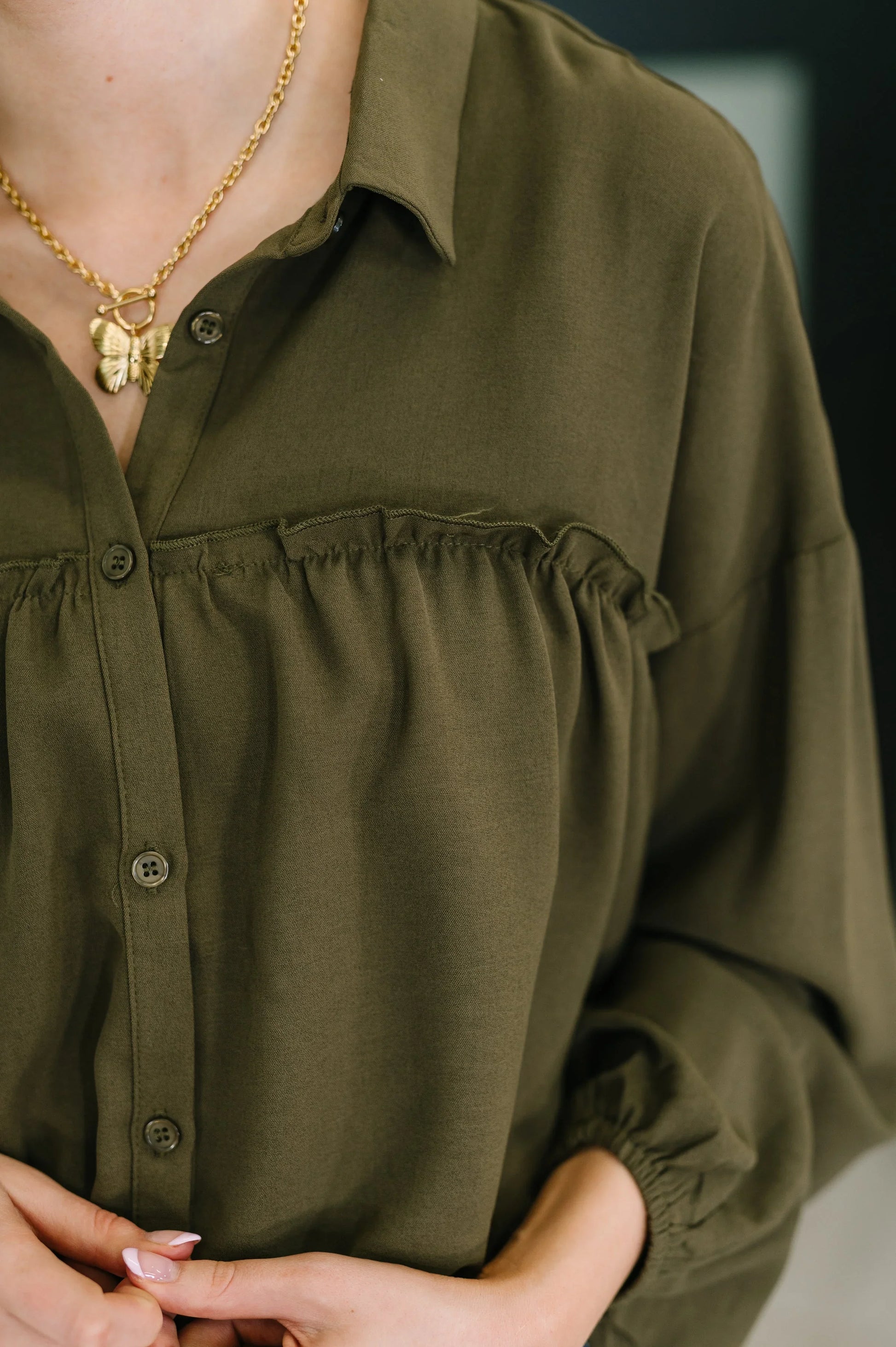 Olive green She’s Got A Way button-up blouse with ruffled hem and gold necklace