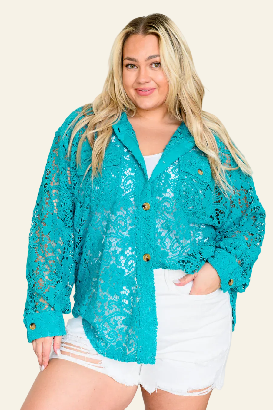Woman wearing a teal lace cardigan over a white top and shorts on a beige background