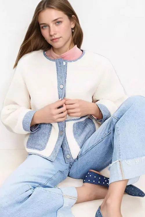 A woman wearing a Sherpa jacket and denim jeans