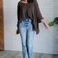 Brown oversized knit top with 3/4 sleeves and high neckline, paired with light blue straight-leg jeans
