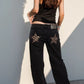 Black denim wide leg jeans with leopard-print star patches on back pockets