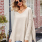 Beige oversized v-neck slit exposed seam sweater with ribbed cuffs