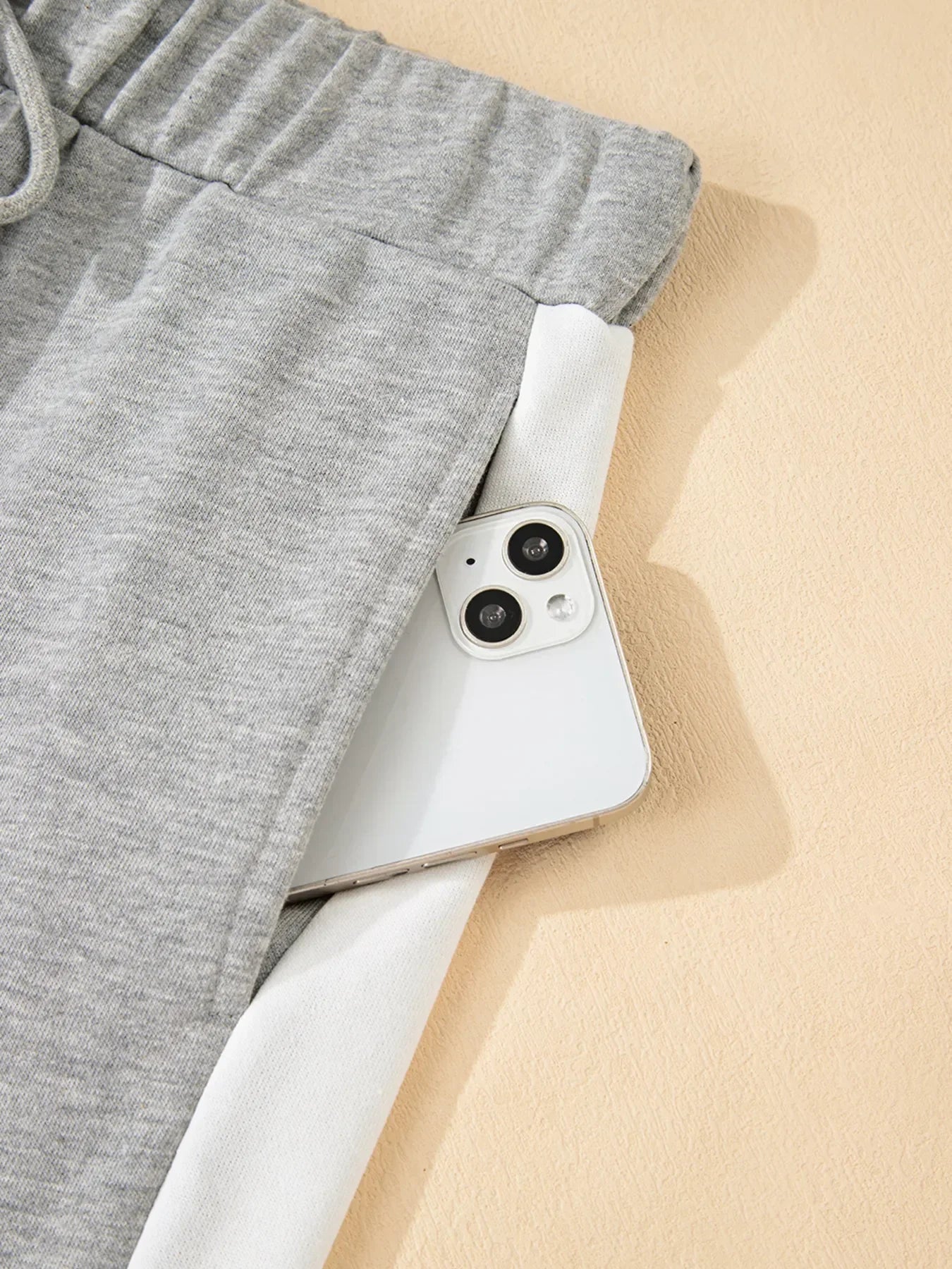 White iPhone 13 on Daverri Fashions grey sweatpants set