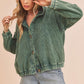 Woman wearing a green corduroy jacket and denim shorts on a beige background