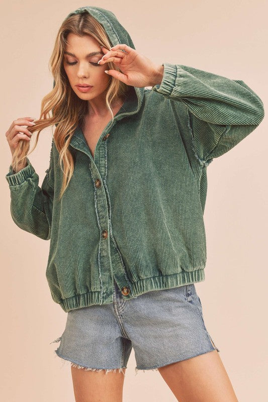 Woman wearing a green corduroy jacket and denim shorts on a beige background