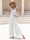 White sleeveless wide leg jumpsuit with tie shoulder straps and subtle embellishments