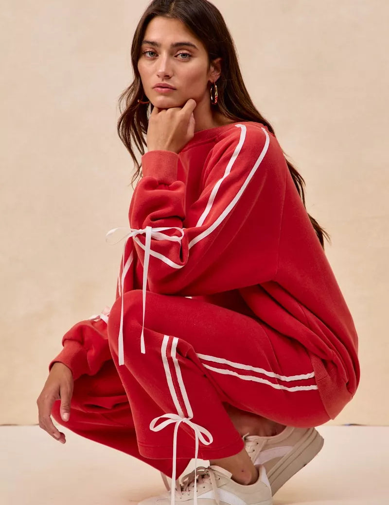Red oversized hoodie with white stripes, drawstrings, and bow details