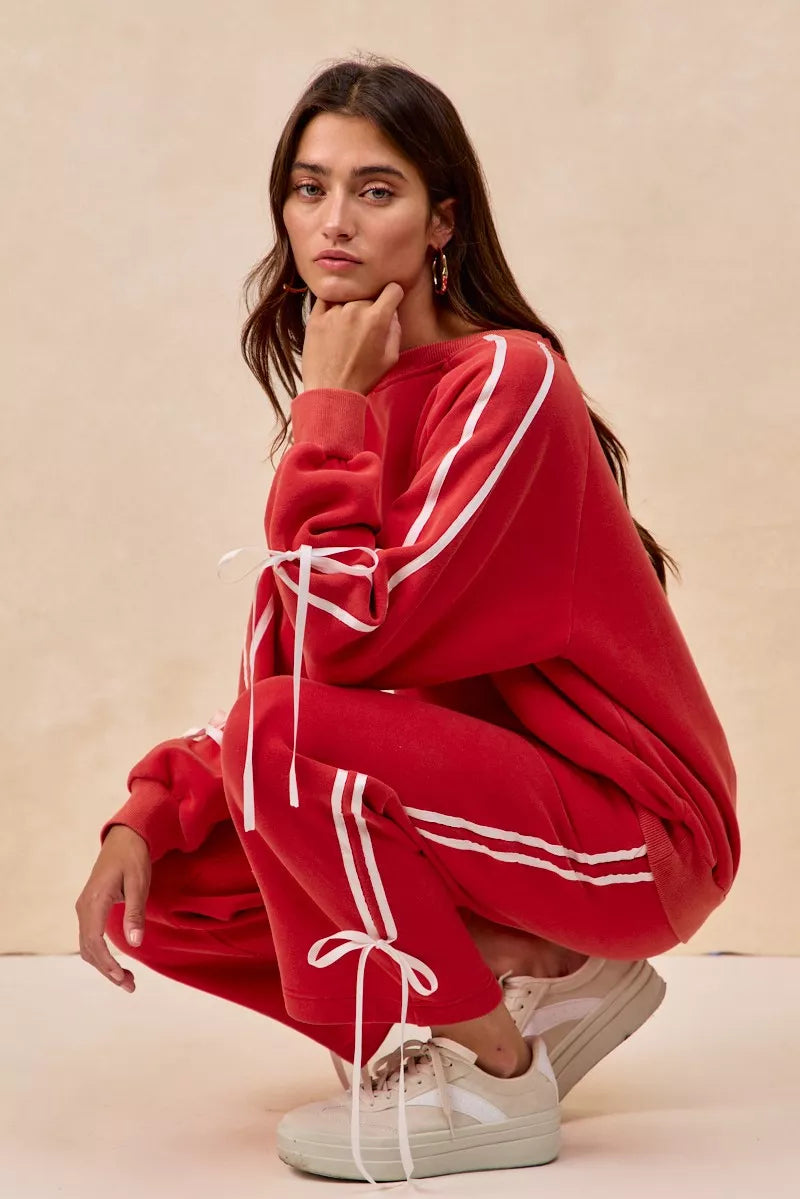 Red oversized hoodie with white stripes, drawstrings, and bow details