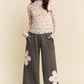 Gray wide-leg pants with pink and white floral patches on lower legs