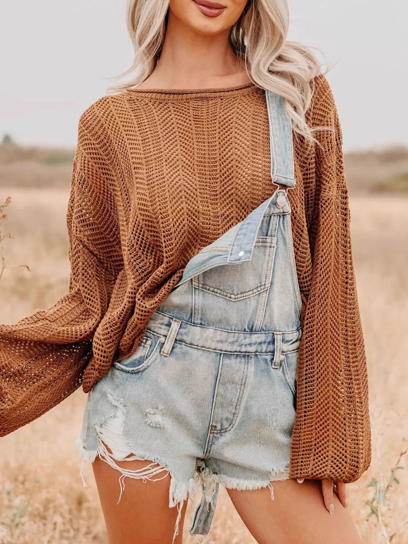Distressed denim overalls shorts with light-wash frayed hem over brown herringbone sweater
