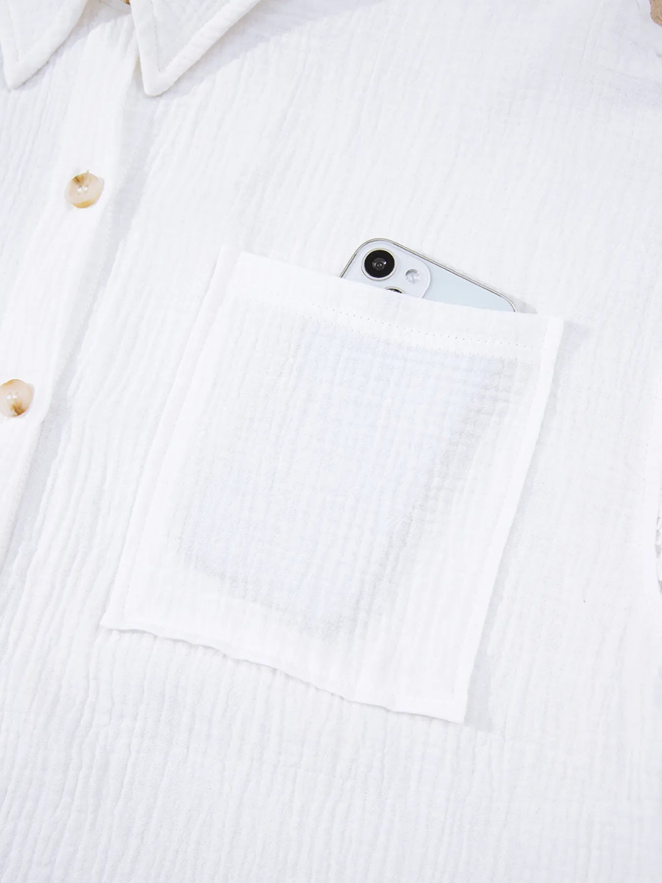 Womens lace sleeve button down cotton shirt with white textured fabric and front pocket holding silver smartphone